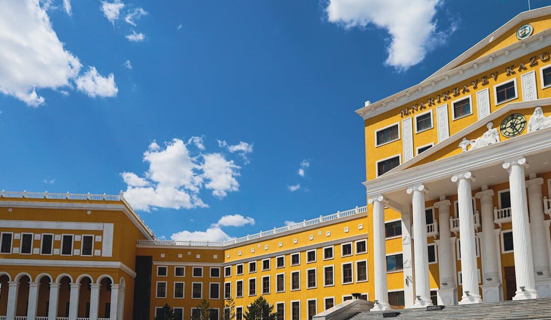 Stunning architectural facade of a university in Kazakhstan against a vibrant blue sky.