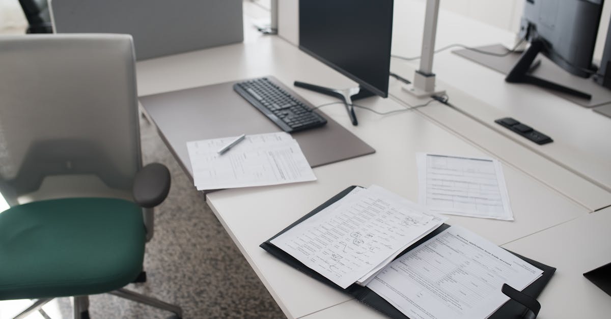 Контакты 1 A clean and organized office desk with documents, a computer, and chair in a modern workspace.