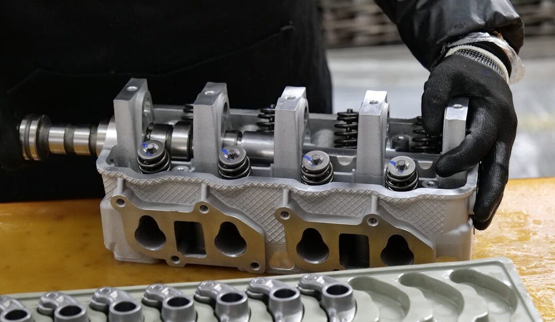 Mechanic assembling an engine cylinder head with precision components on a workbench.