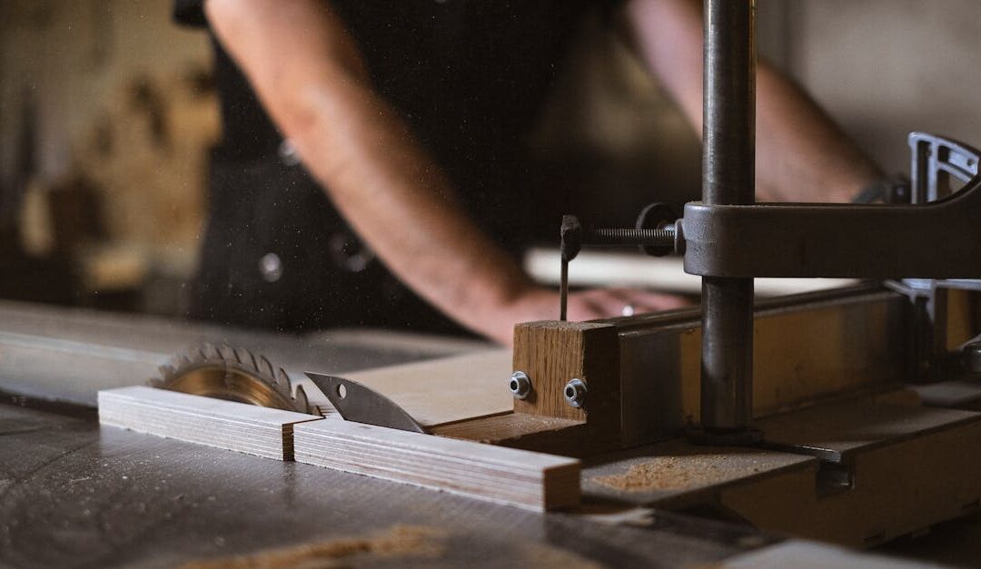 Unrecognizable blurred male carpenter cutting wooden details at sawbench with sharp knives while working in professional