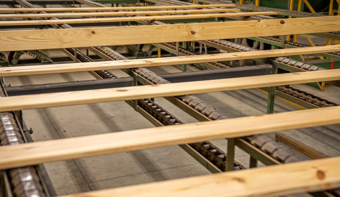 Close-up of wooden planks on a production conveyor in a factory setting.