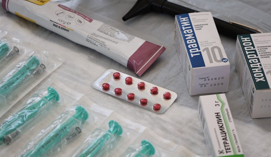 Flat lay of medical supplies including syringes, pharmaceuticals, and an otoscope on a table.