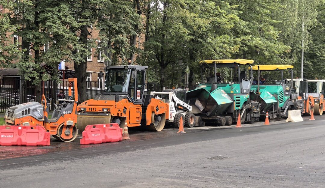 Heavy machinery for roadwork lined up on an urban street during daytime construction.
