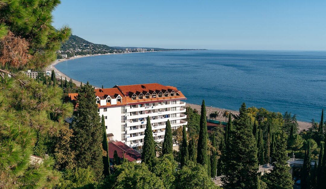 Explore Gagra's stunning coastal landscape featuring a beachfront hotel and lush greenery.