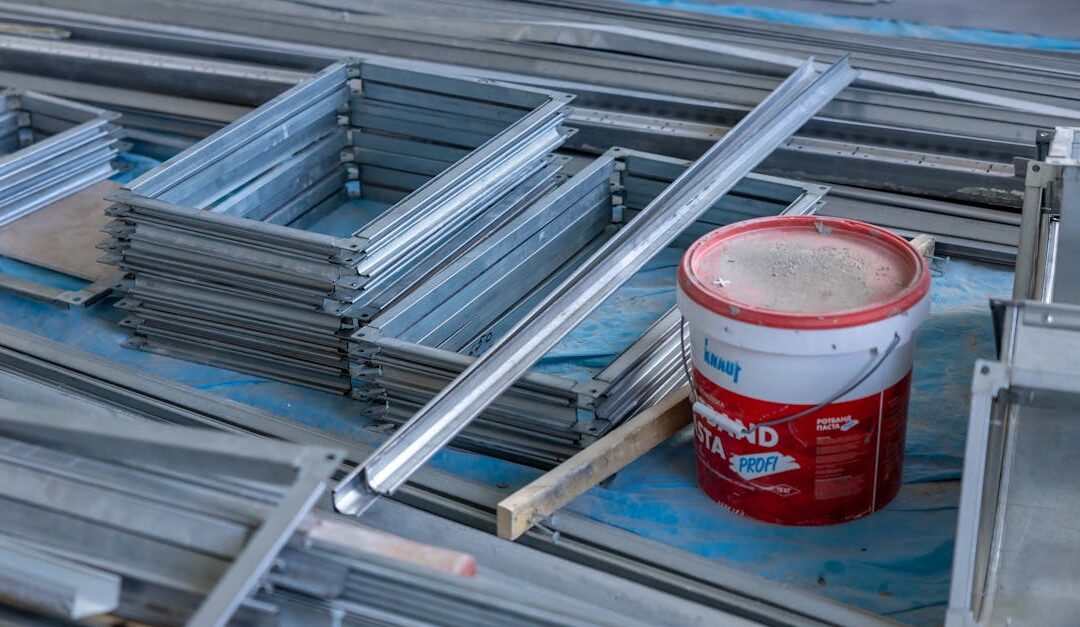 Stacks of metal frames and a paint bucket inside a construction site emphasizing building materials.