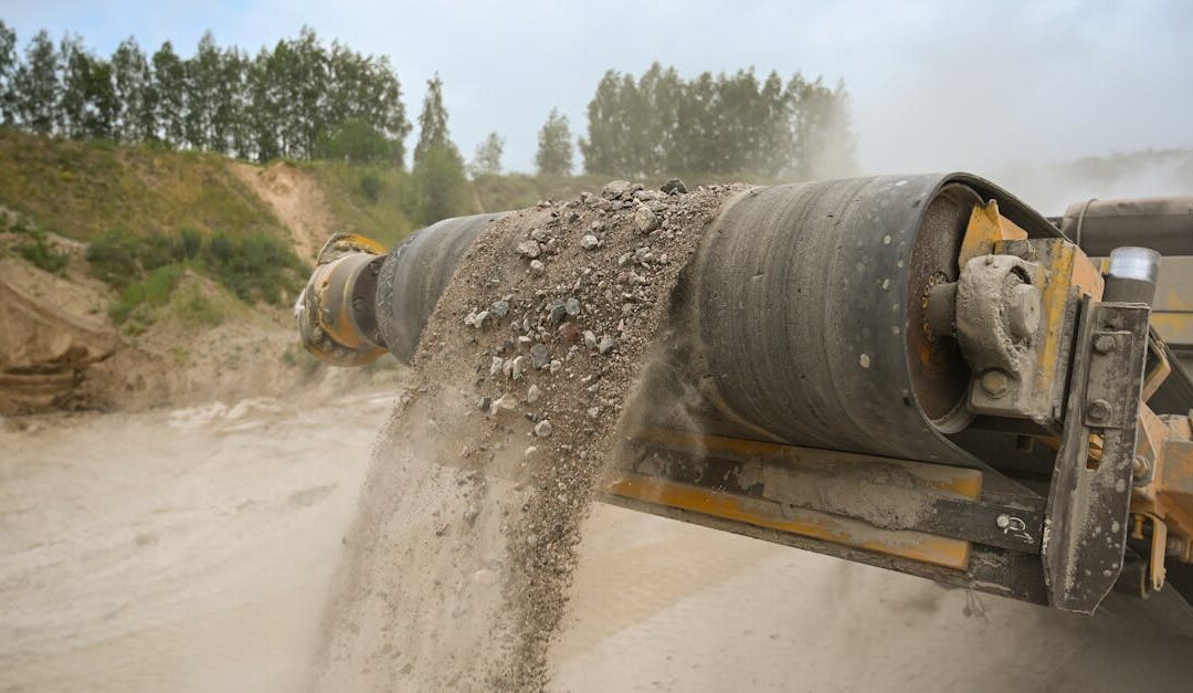 A close-up of an industrial conveyor belt moving gravel at a construction site