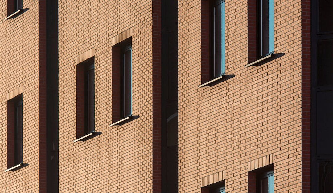 Close-up of a brick building façade with sunlight highlighting windows, a classic urban architectural design.