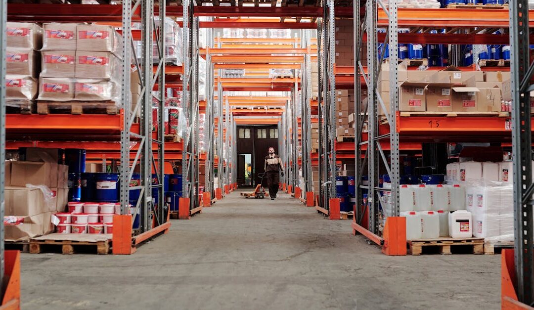 A spacious industrial warehouse with stocked shelves and a worker in protective gear.