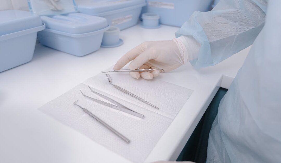 Close-up of dental tools on a table with a dentist in surgical gloves, showcasing a clean healthcare environment.