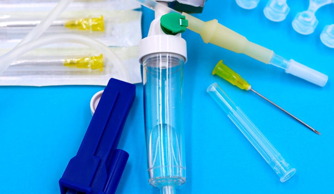 Collection of sterile medical tools including syringes and tubing against a blue backdrop.