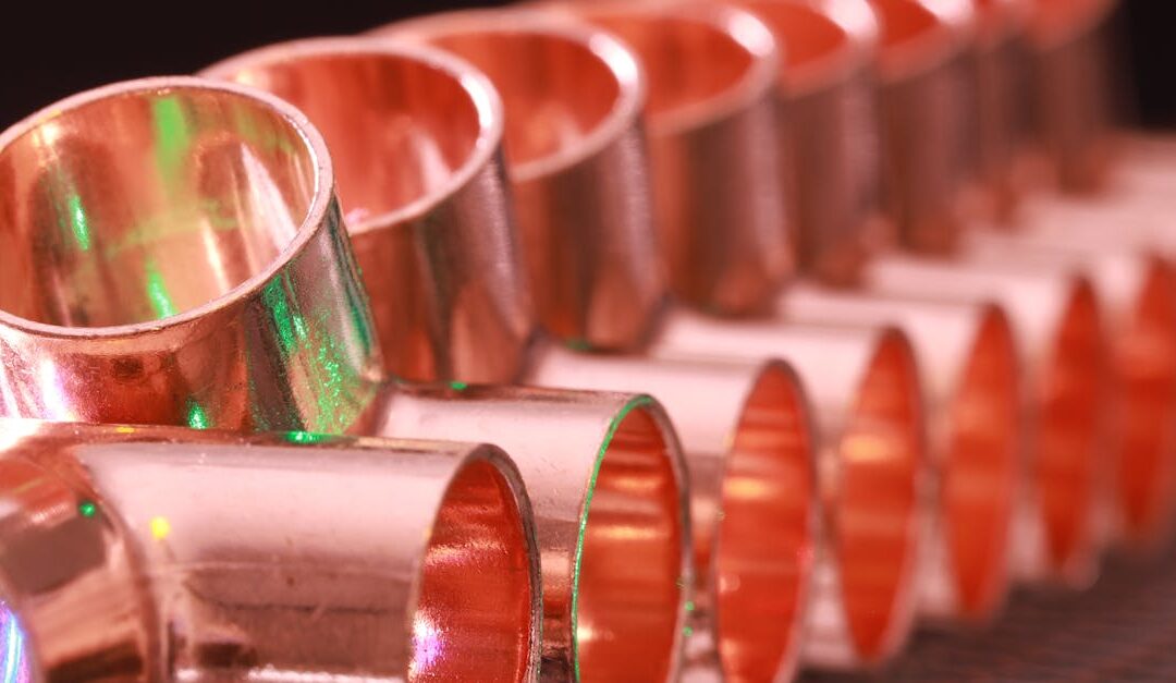 Copper plumbing fittings arranged in a row, showcasing metallic texture and industrial detail.
