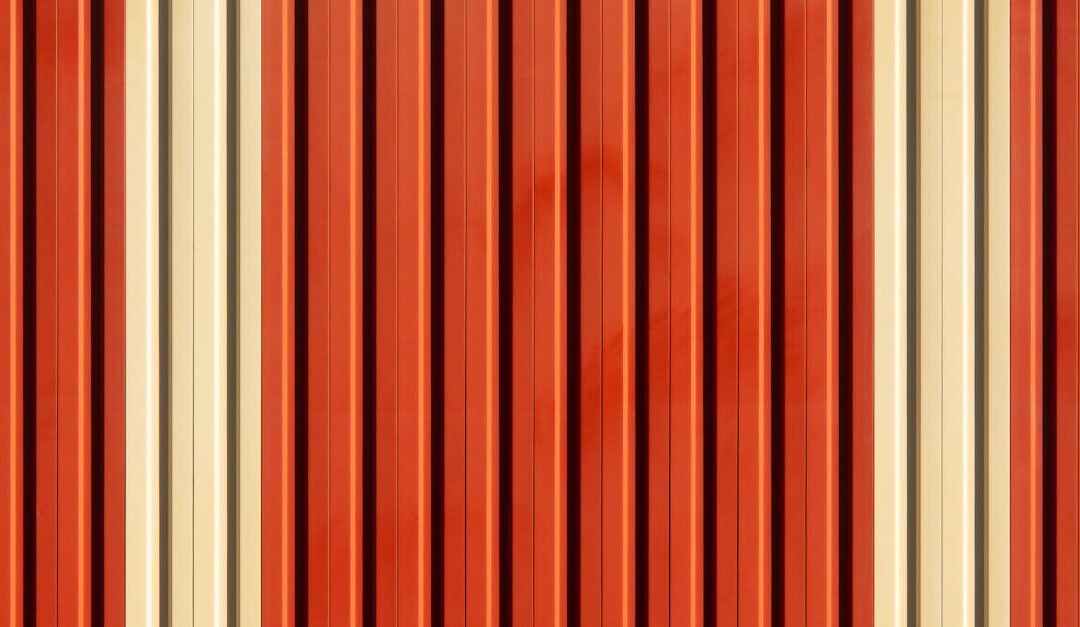 Close-up view of vertical striped pattern on a red and beige metal facade.