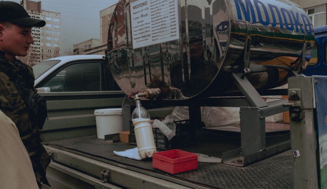 Military personnel at a mobile milk tank distribution point in an urban setting.