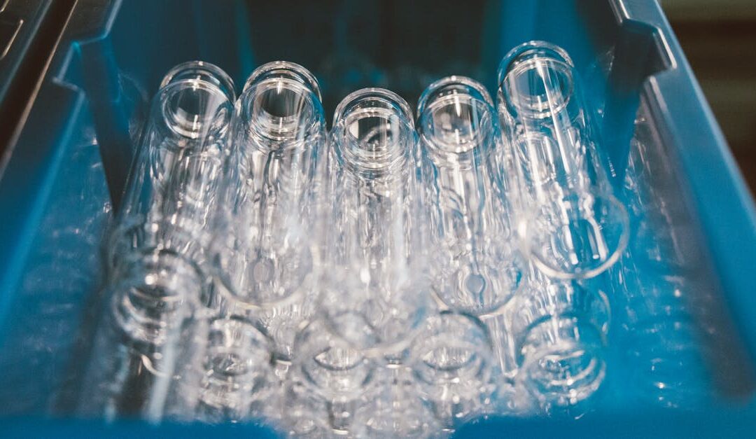 A collection of empty glass test tubes stored in a blue laboratory tray under bright lighting.