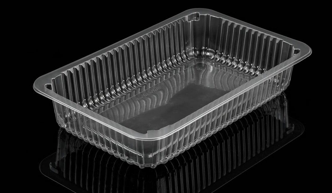 Empty clear plastic food container with reflections against a black background.