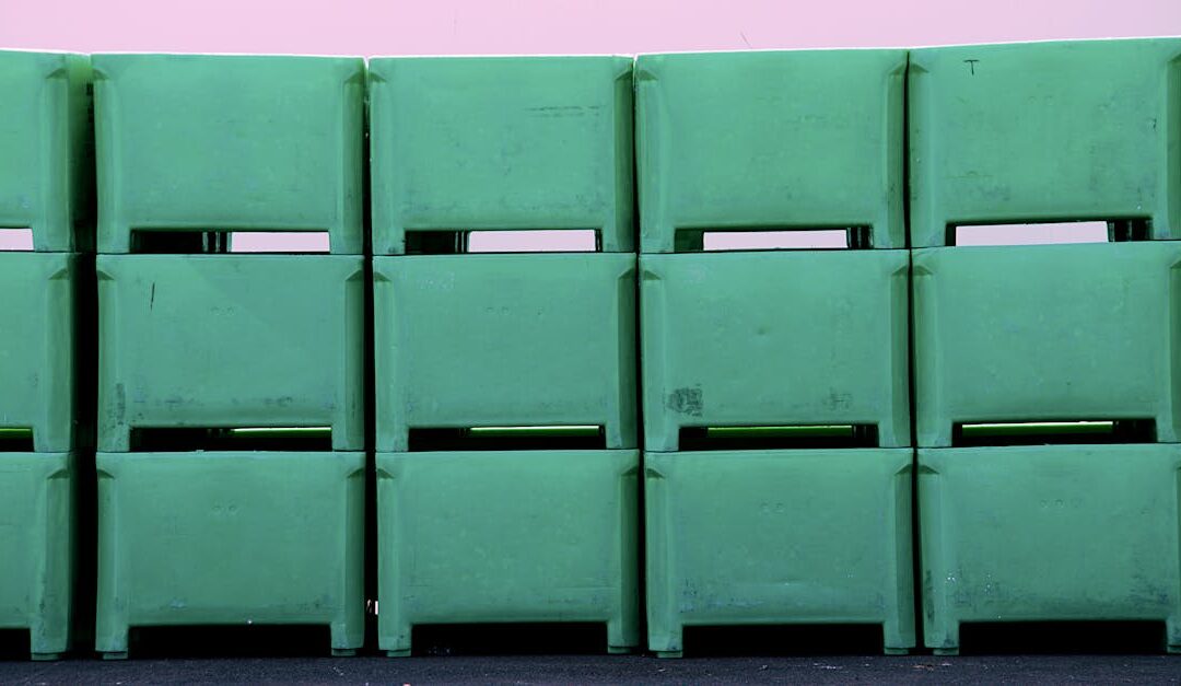 Row of green plastic tubs stacked against a pink wall. Industrial and storage concepts.