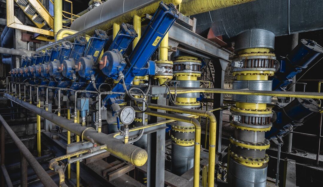 A detailed view of an industrial machine room featuring complex blue and yellow equipment and piping.