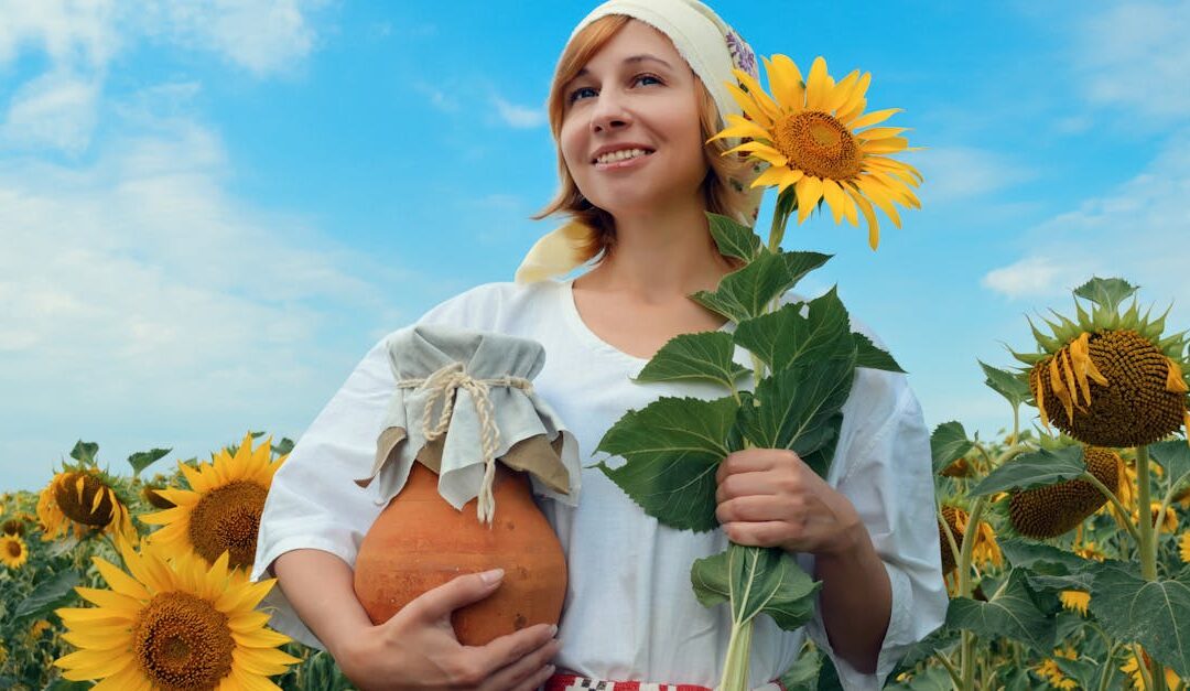 Low angle of cheerful female peasant with handmade jug and sunflower on rural field