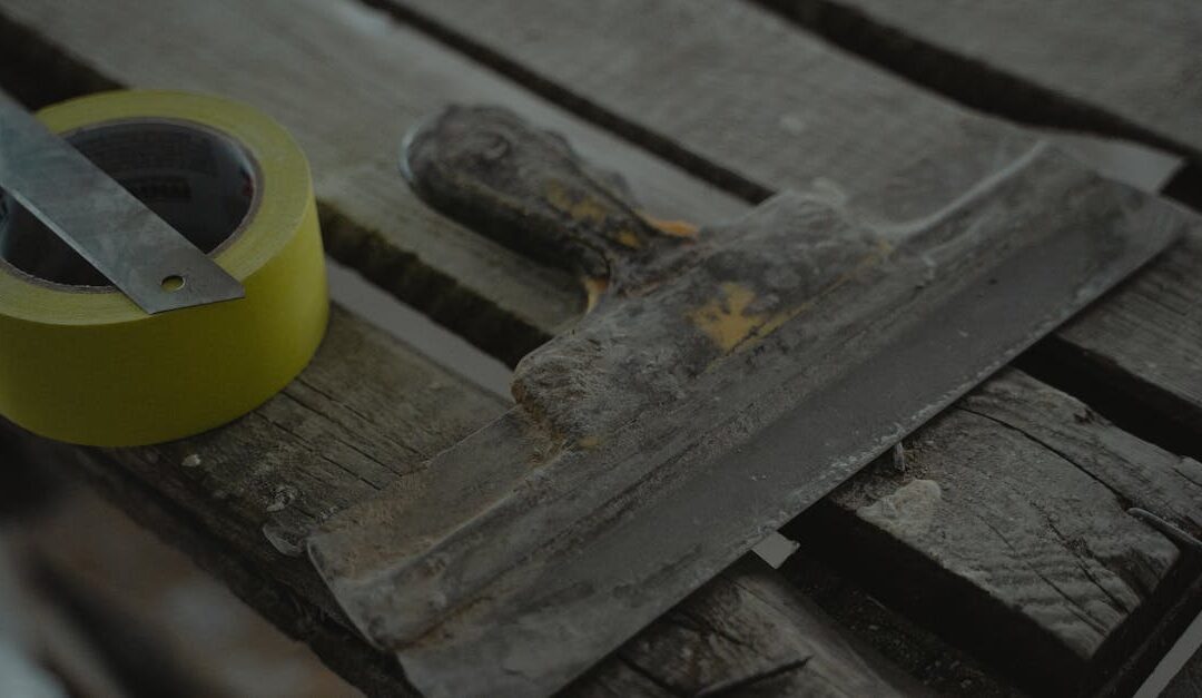 Close-up of a spatula and duct tape on an aged wooden surface. Perfect for DIY and renovation themes.