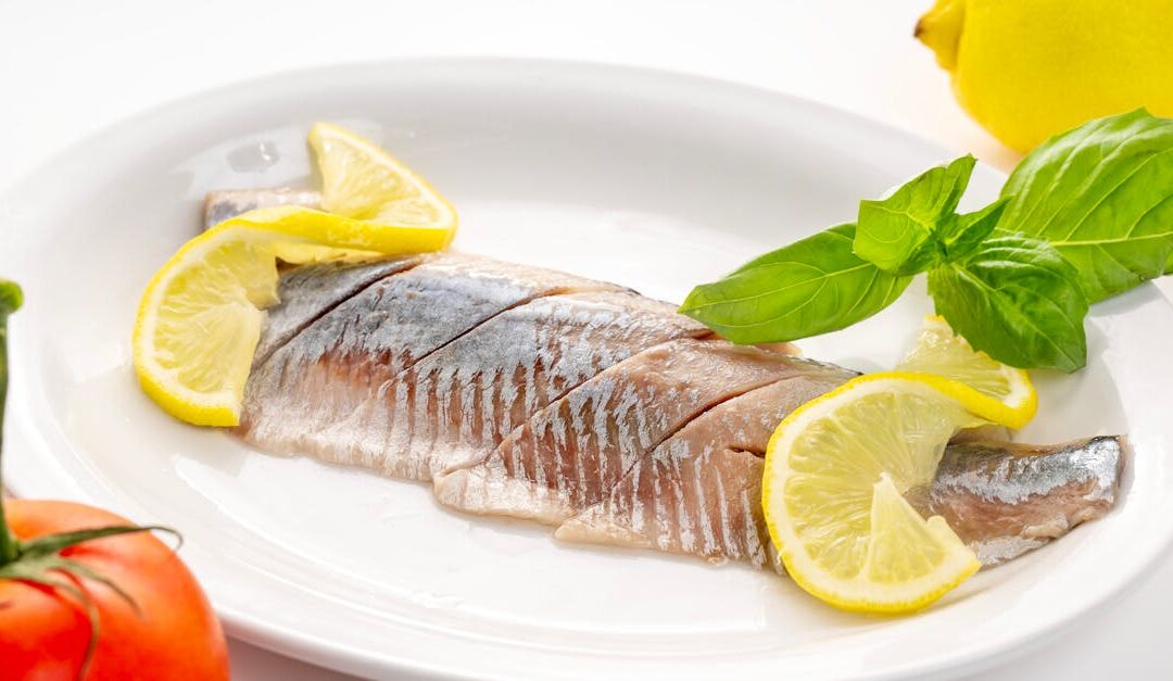 Delicious fresh fish fillet garnished with lemon slices and basil, served on a white plate.