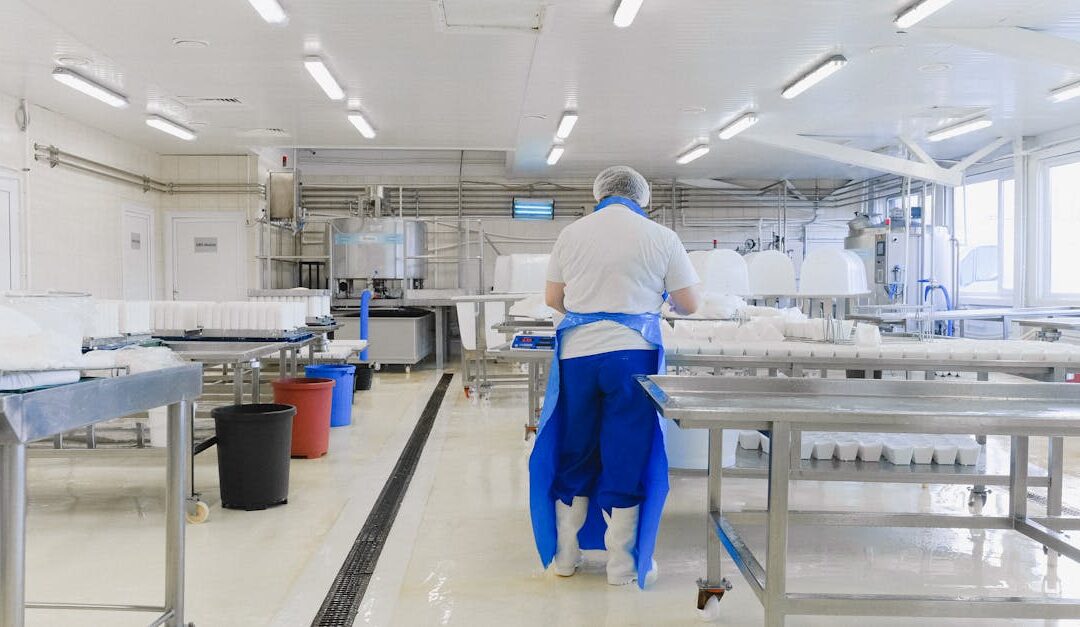 A person wearing protective clothing working in a bright, sterile laboratory environment.