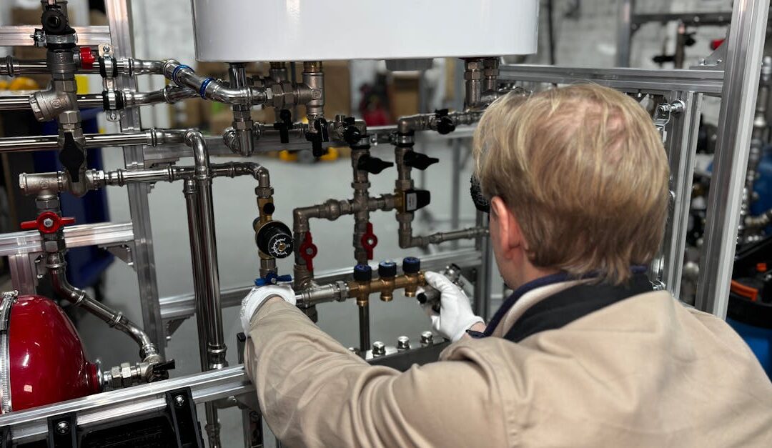 Engineer working on industrial pipe system in a factory for heating and production adjustment.