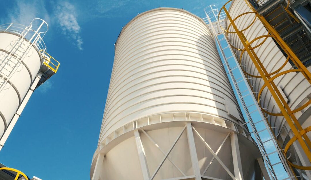 Wide-angle view of industrial silos with clear blue sky, captured during daytime, showcasing modern industry.