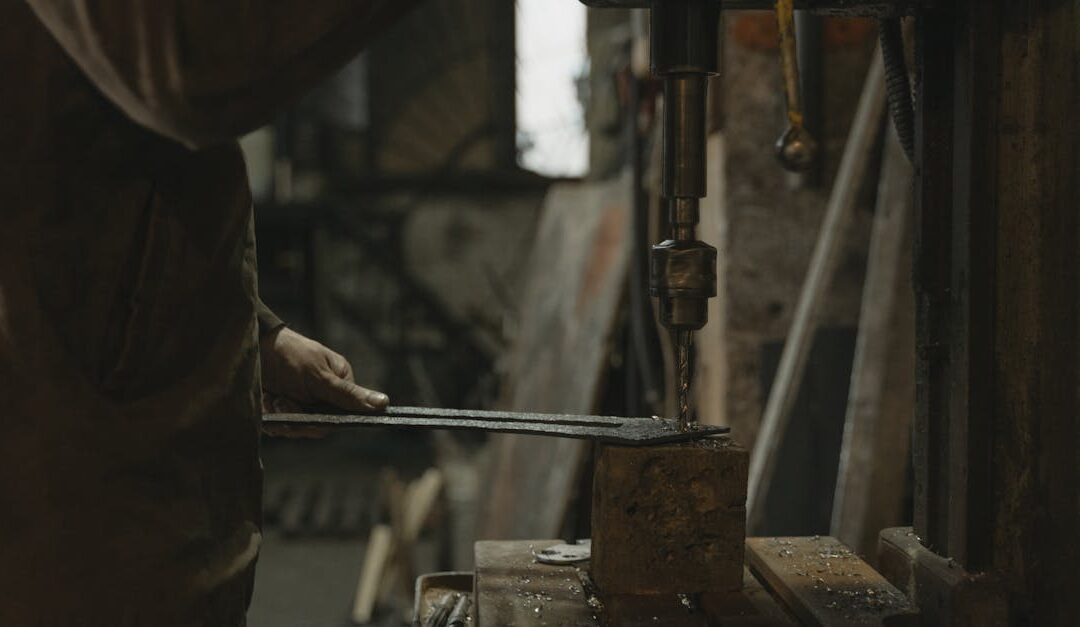 A craftsman uses a drill press indoors, showcasing industrial craftsmanship and precision.