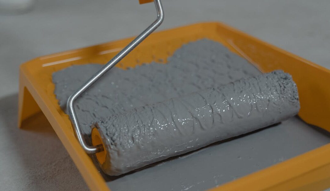 Detailed view of a gray paint roller placed in an orange tray, ready for painting.
