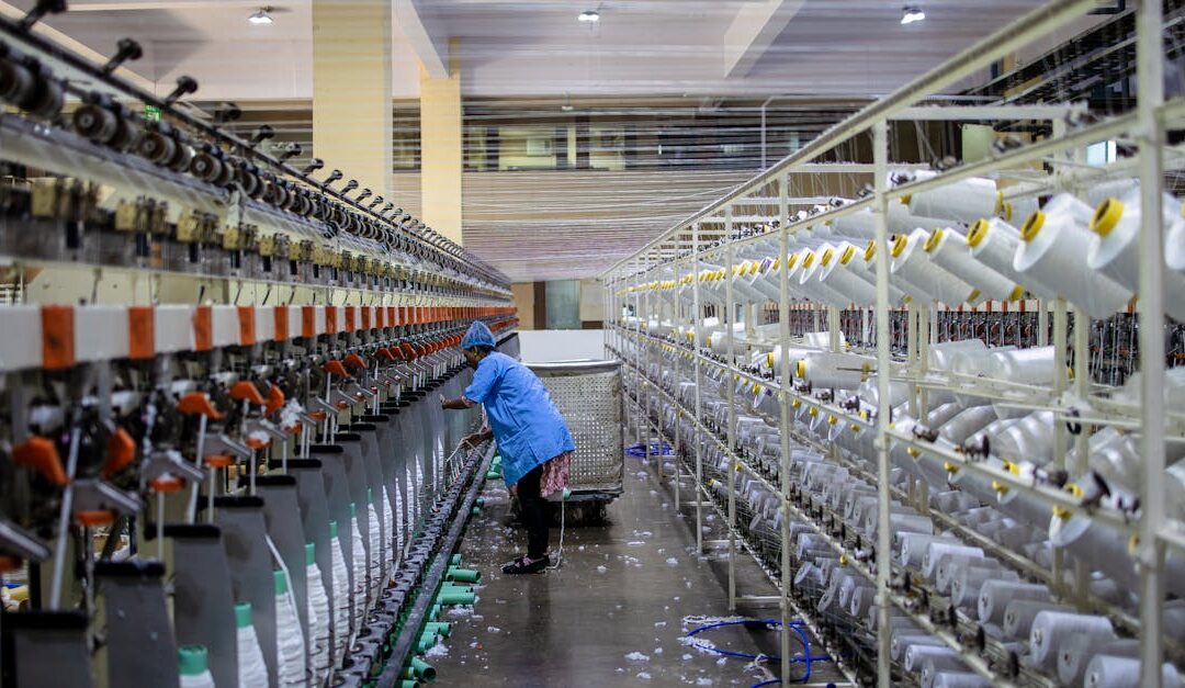 A textile worker handling machinery in a modern factory setting.