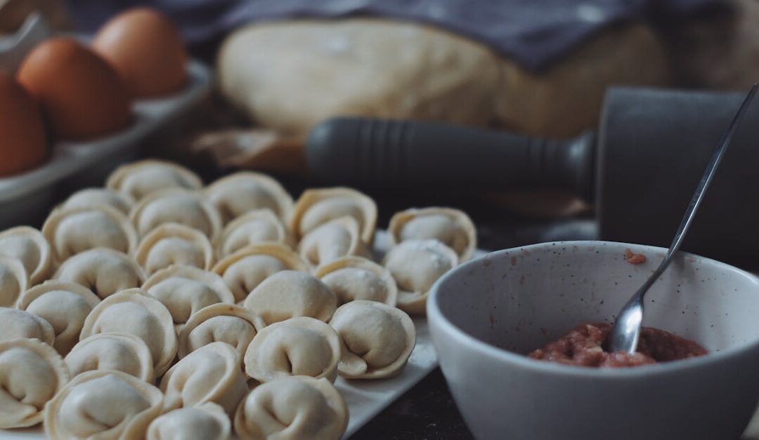 Raw dumplings ready for cooking with dough and filling on a kitchen counter.