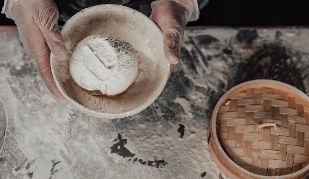 Close-up view of artisan bread dough preparation using bamboo steamer, hands in gloves handling flour.